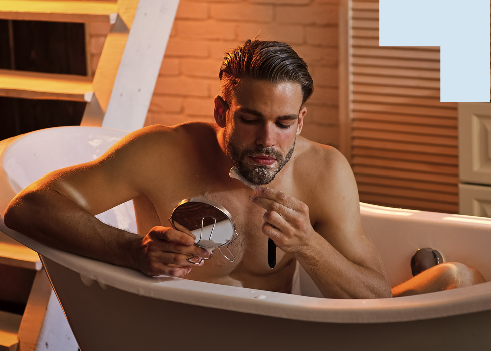 Man scheert zijn baard in het bad